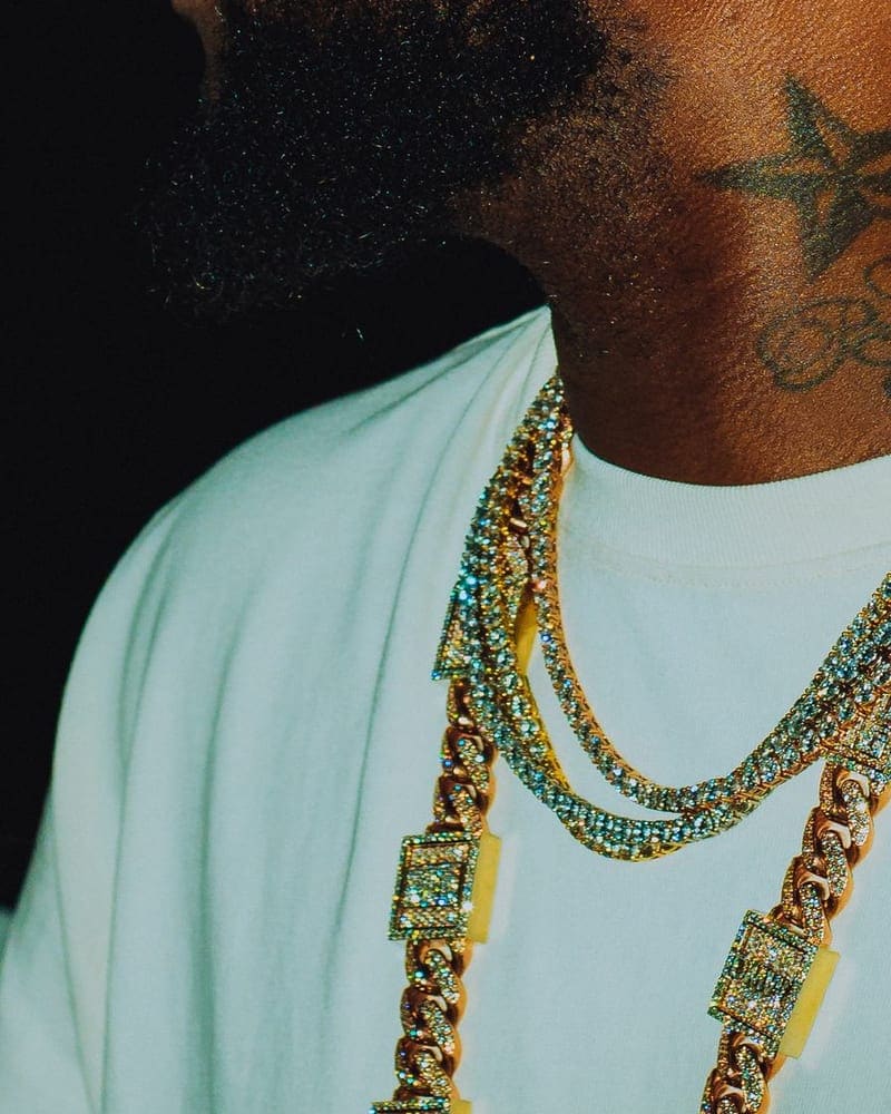 Stacked diamond-set gold link chains worn over a white tee