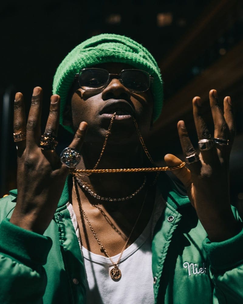 Man in a green beanie holding up layered chains