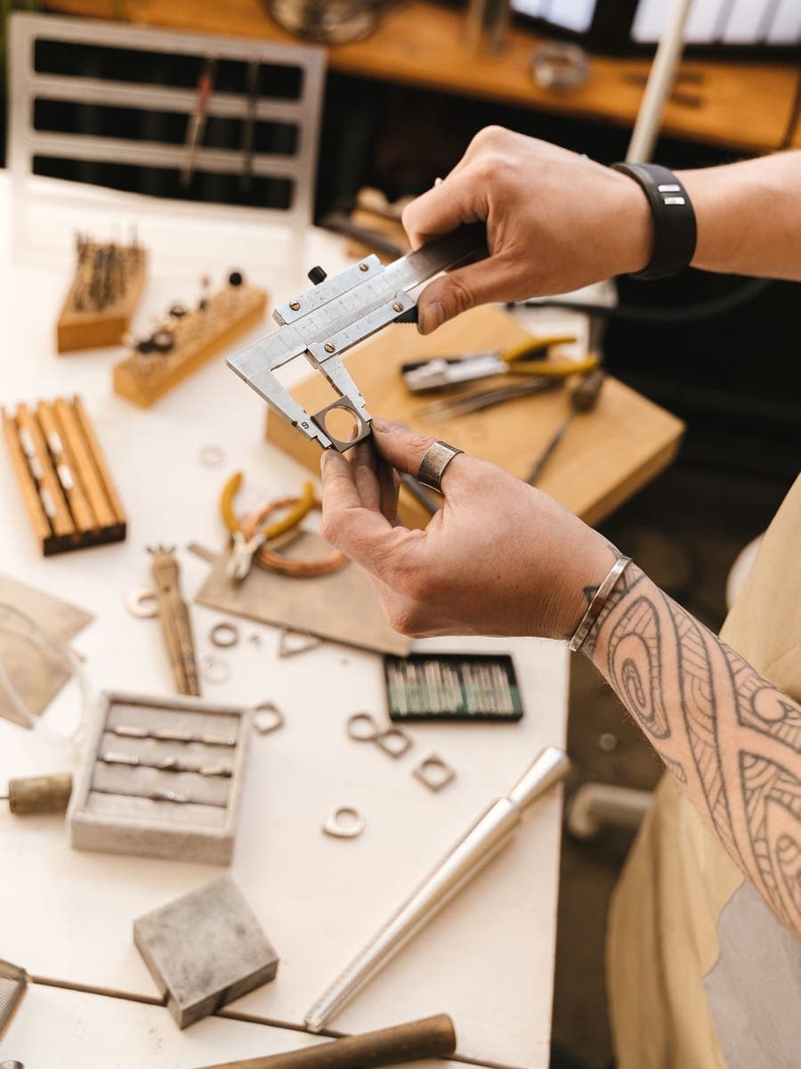 Jeweler measuring a ring with calipers on a bench of tools