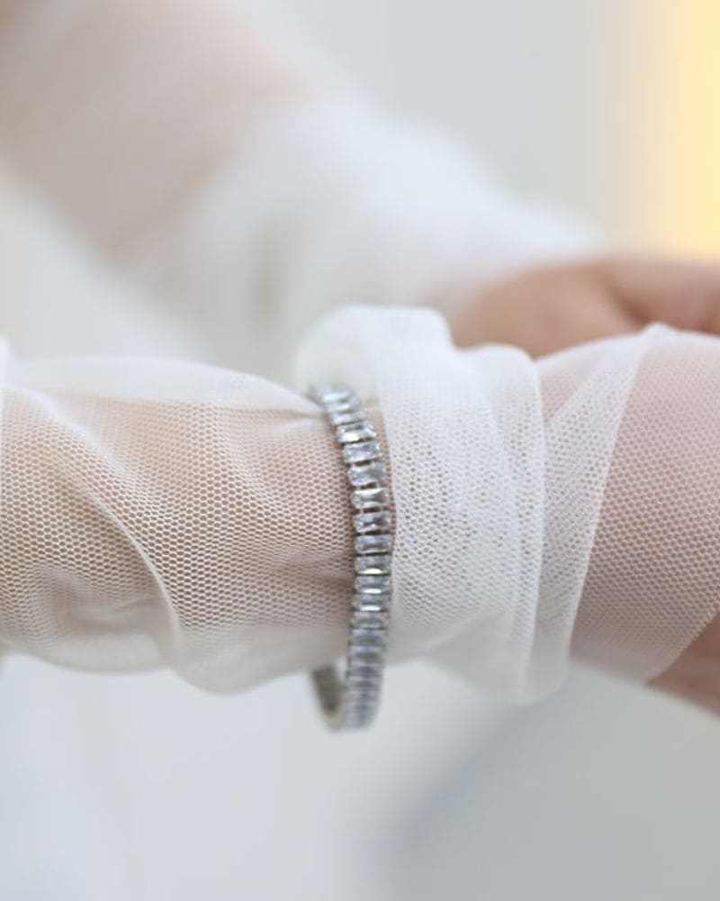 Diamond tennis bracelet worn over a sheer bridal sleeve