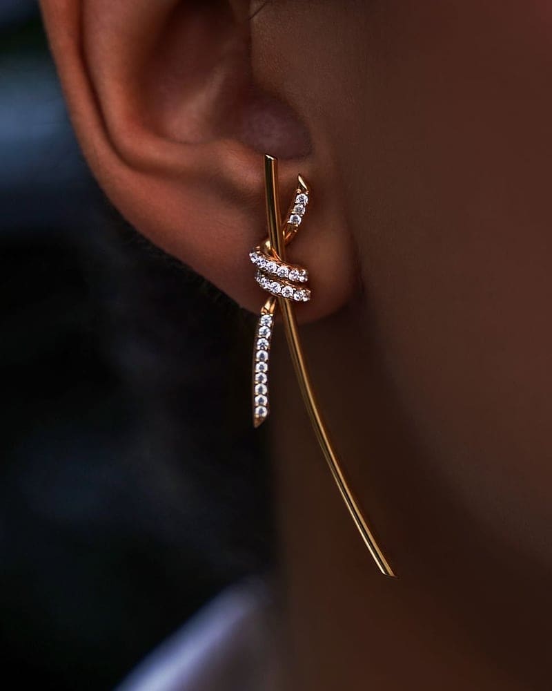 Gold and diamond drop earring worn with a long fine chain