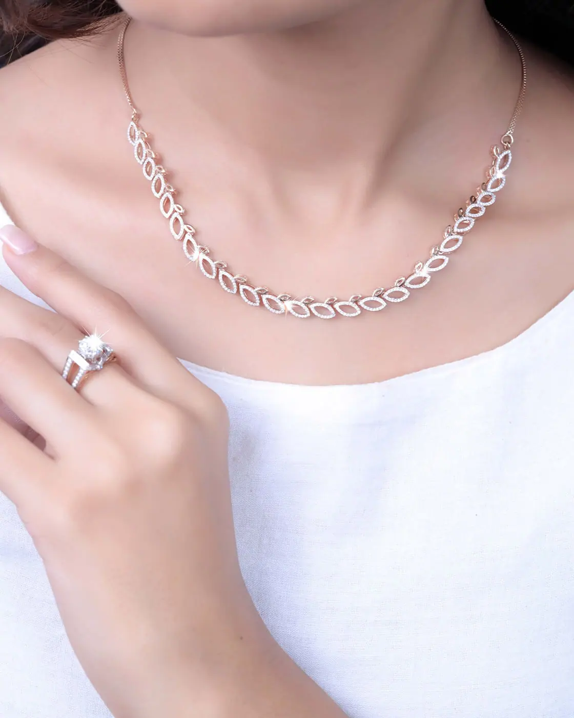 White-gold diamond link necklace worn at the neckline with a cocktail ring