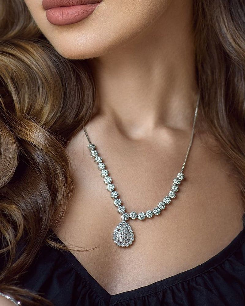 Woman with long waves wearing a diamond necklace with a pear drop