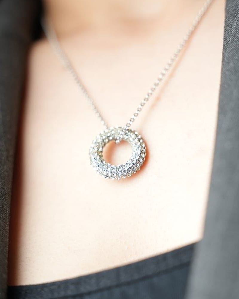 Pavé diamond circle pendant worn with a grey blazer