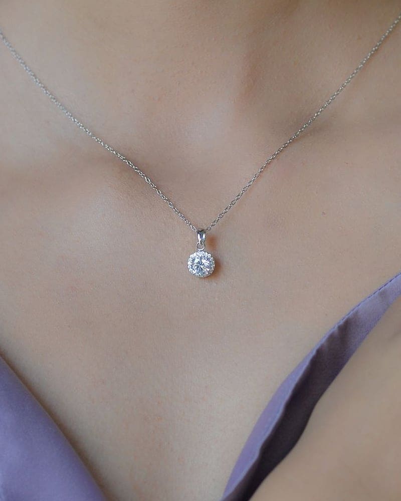 Single diamond solitaire pendant on a fine chain at the collarbone