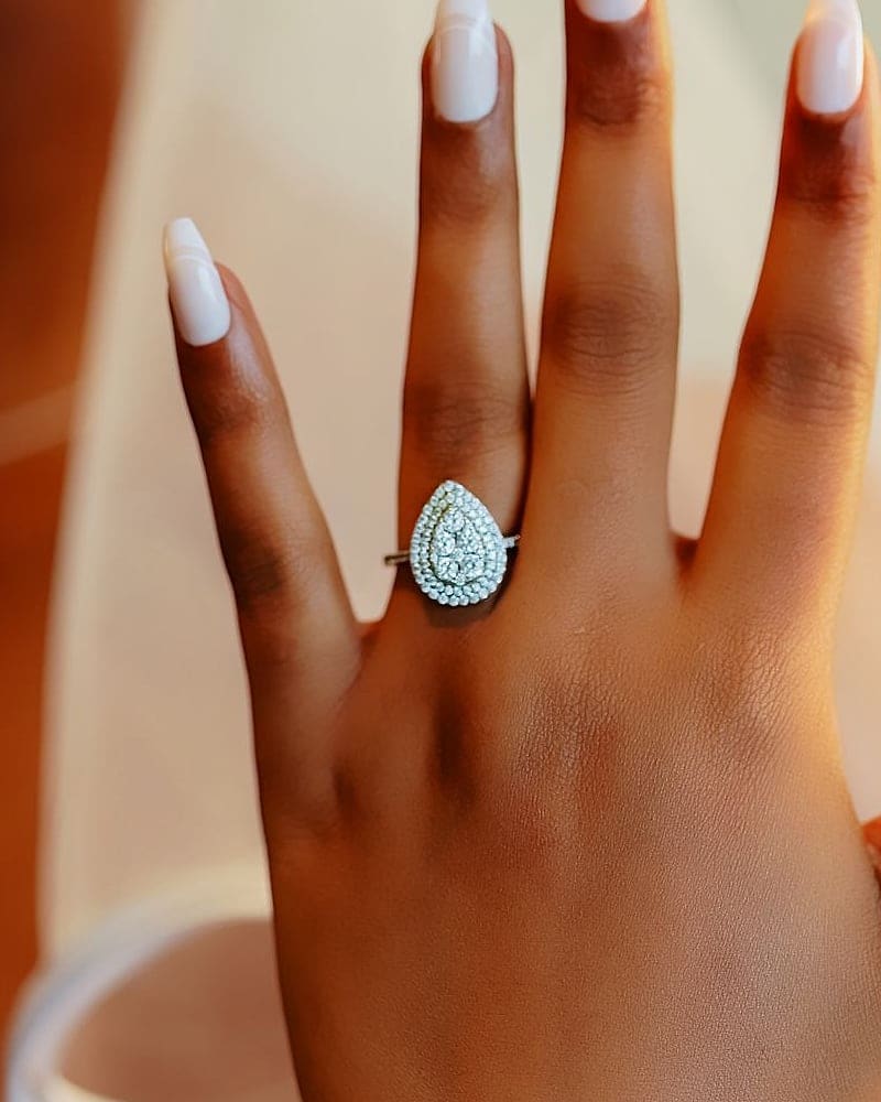 Bride’s hand wearing a pear-cut diamond halo engagement ring