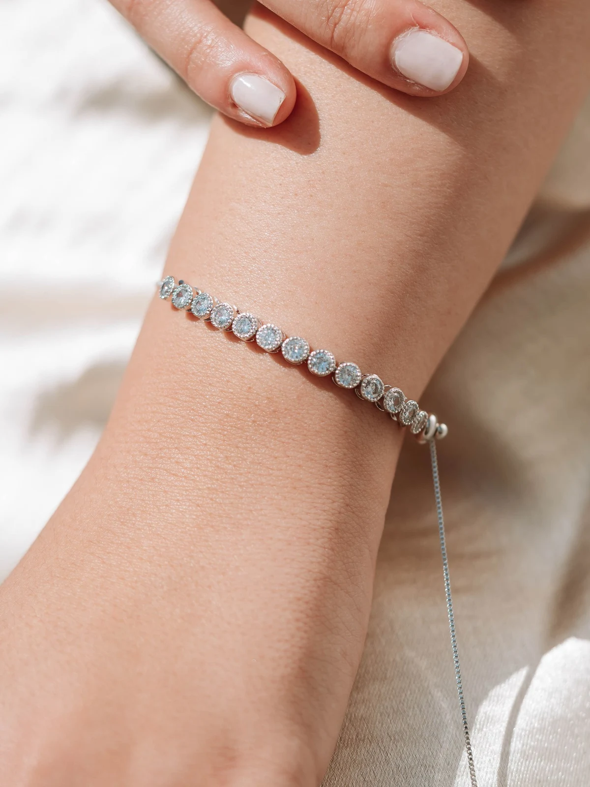 Diamond tennis bracelet worn on a wrist in soft natural daylight