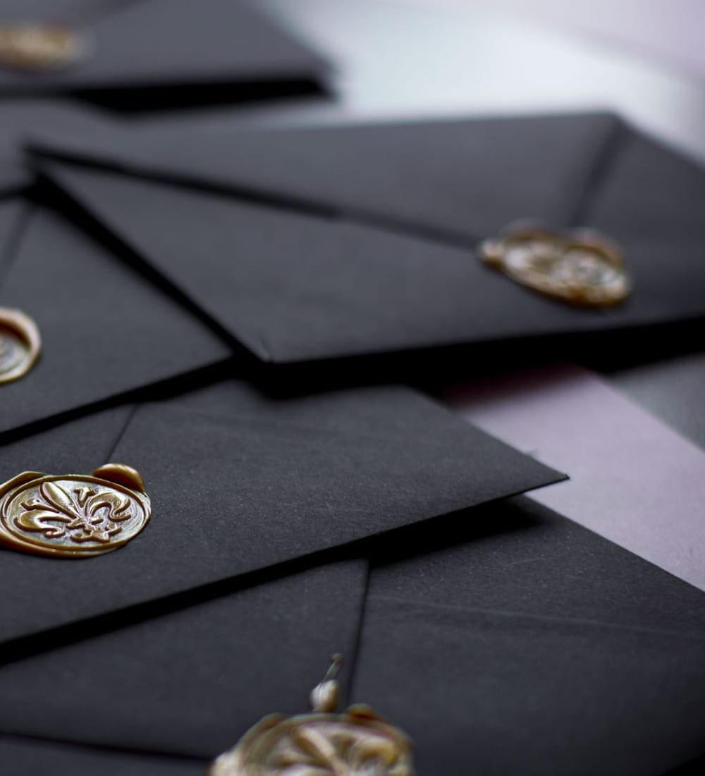 Black envelopes closed with gold wax seals
