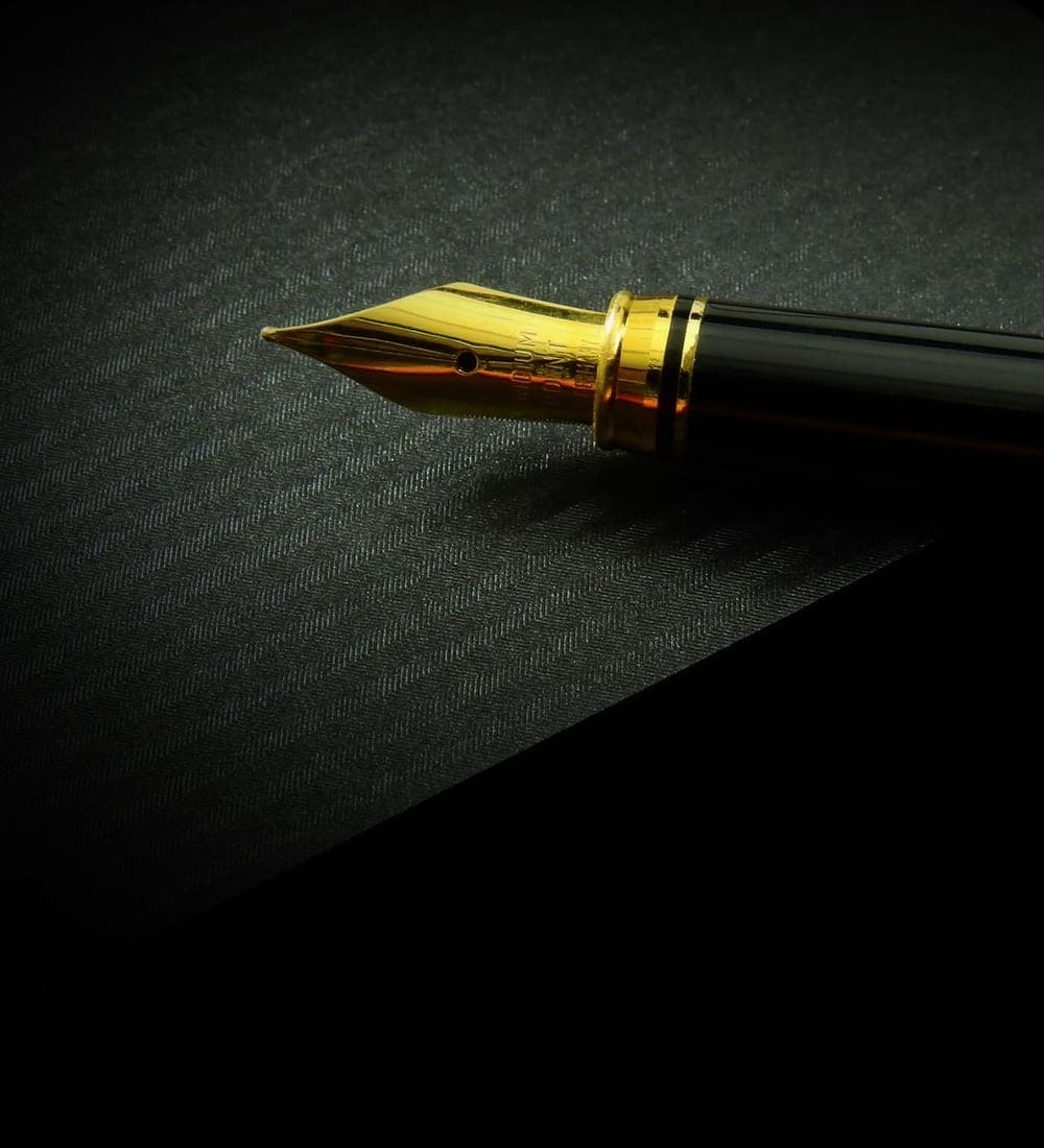 Gold fountain pen resting on black paper