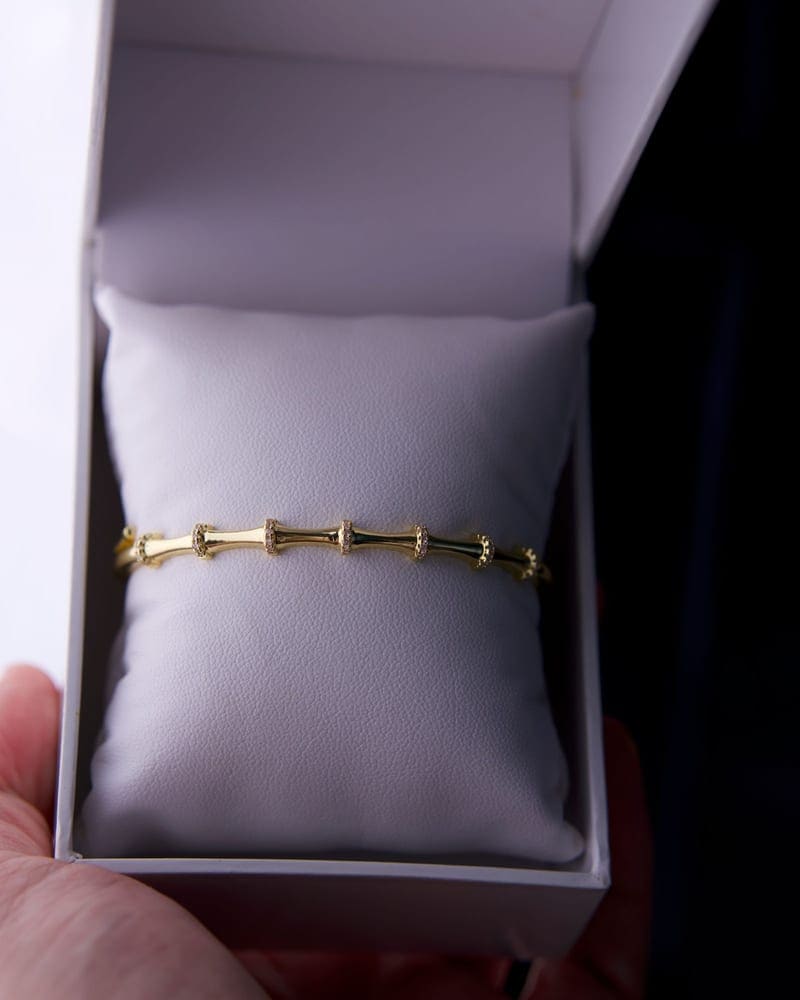 Black gift box being wrapped by hand with ribbon