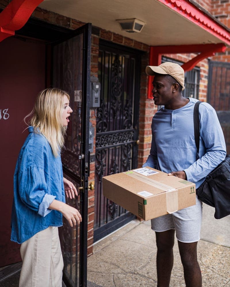 Courier handing a package to a client at her front door