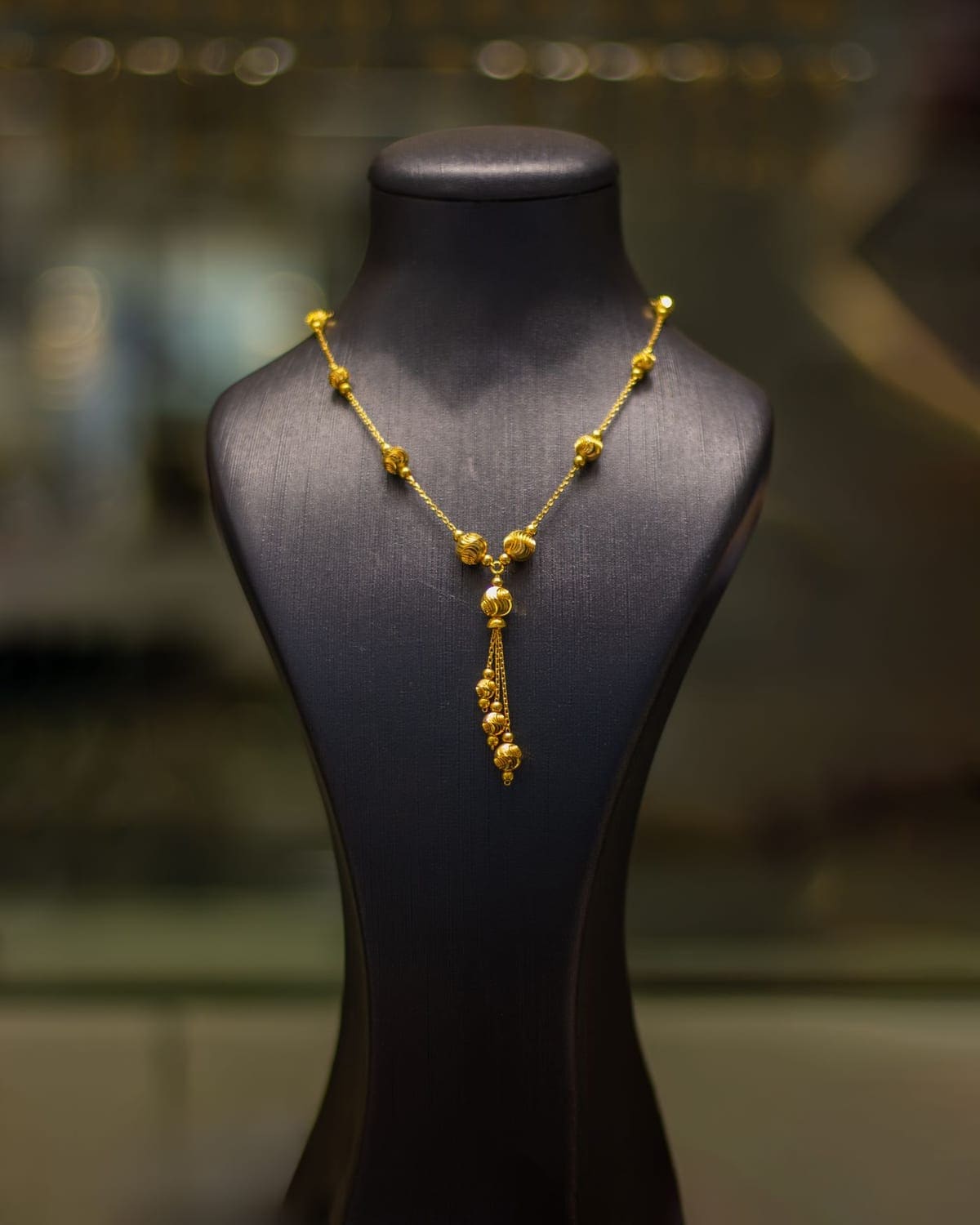 Gold beaded necklace displayed on a velvet bust in the atelier