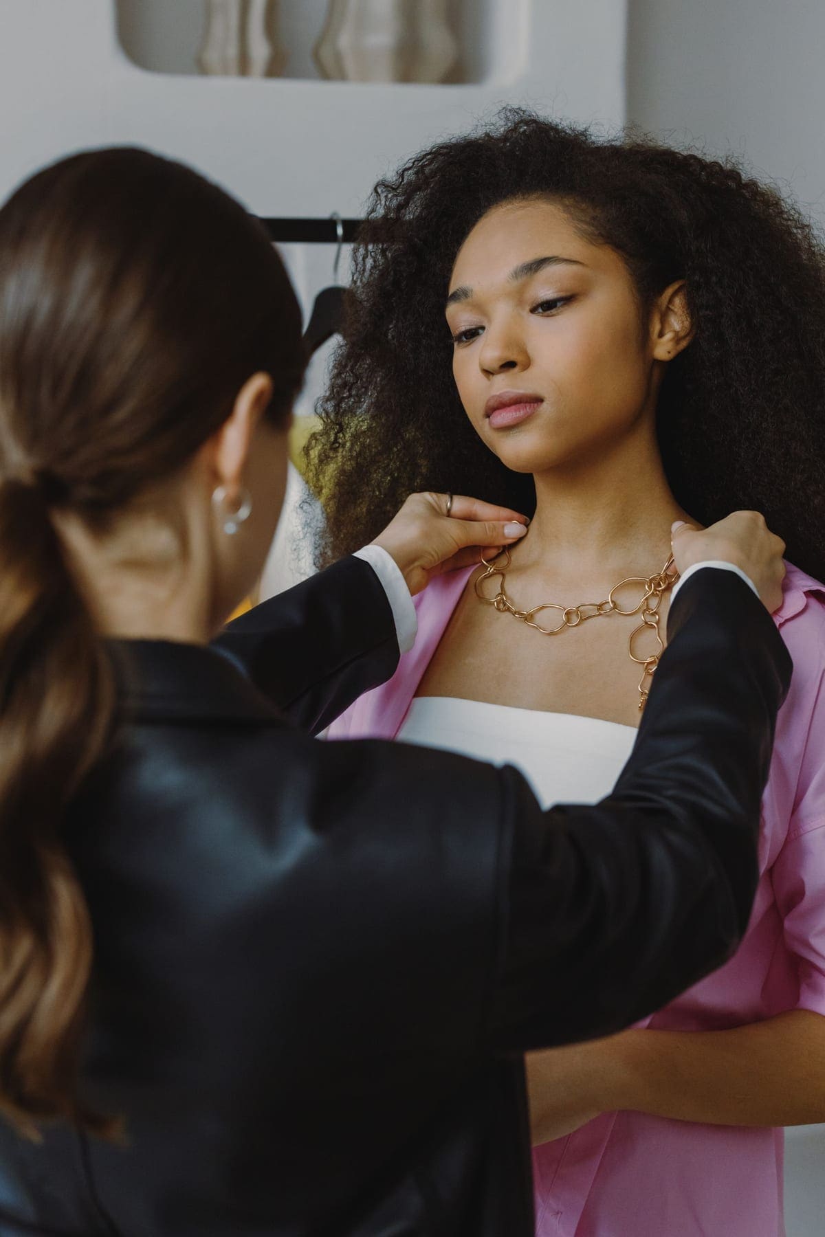 Stylist fastening a necklace on a client in a boutique